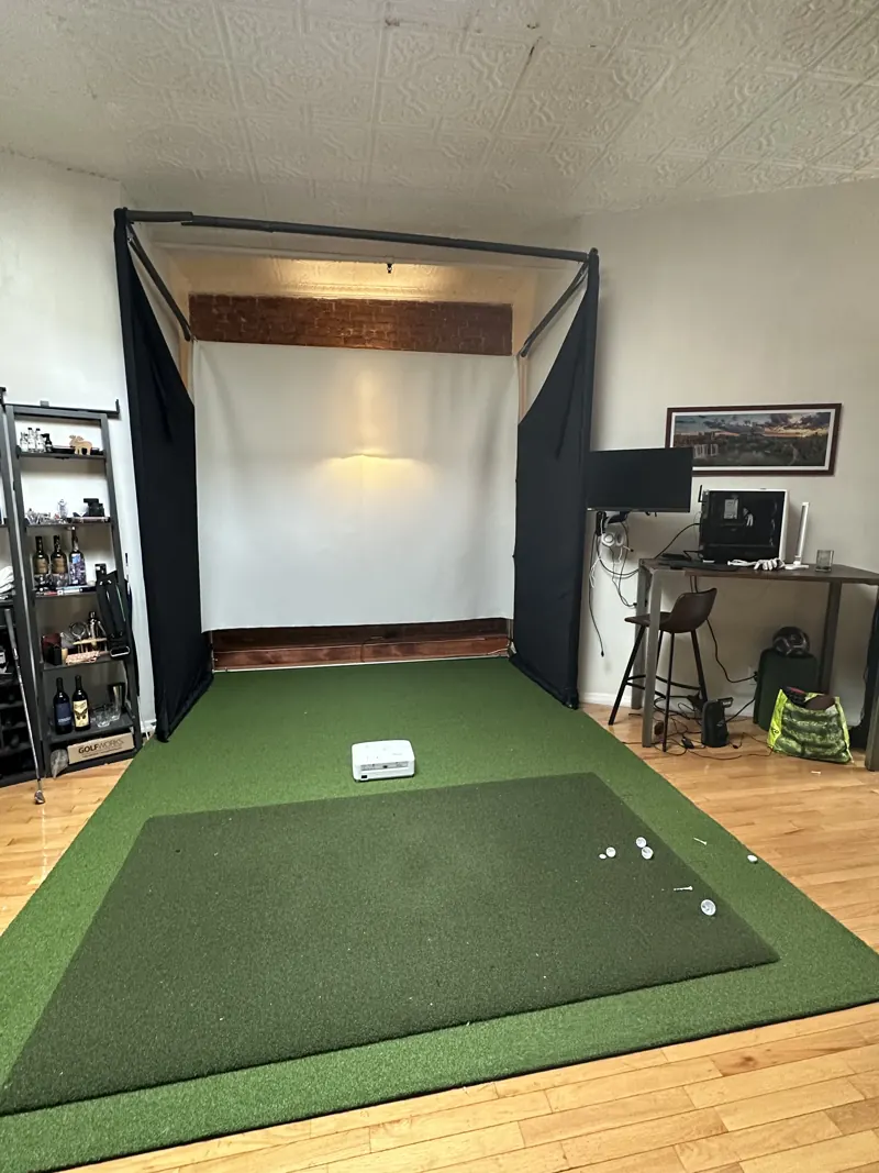 Hitting bay with a turf mat, impact screen, and launch monitor